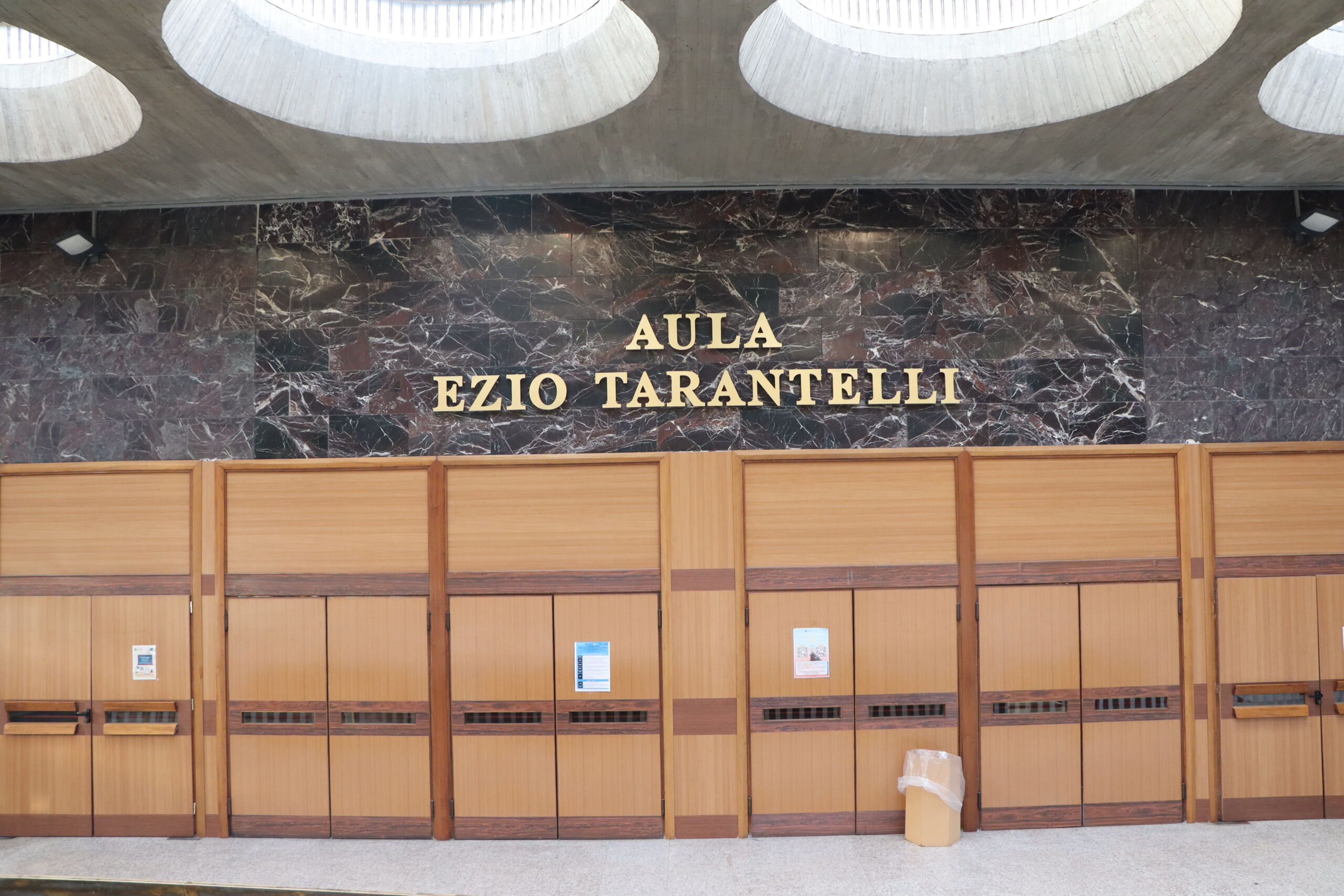 Entrance to Aula Ezio Tarantelli, a lecture hall with wooden doors and marble wall signage